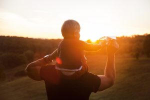 Father with Son on shoulders in sunset paper plane